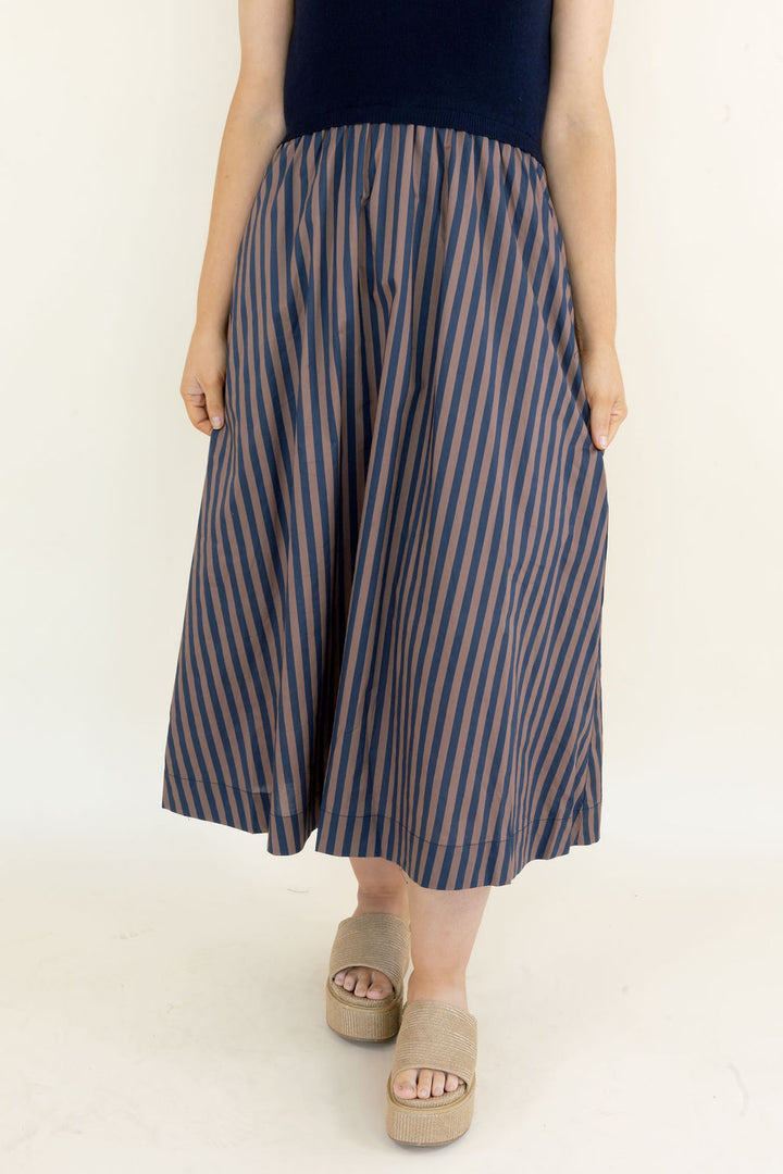 Close-up of navy and brown striped midi dress skirt showing the gathered waist, vertical stripe pattern, and flowy silhouette