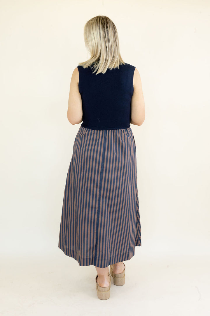 Full back view of navy sleeveless midi dress showing solid navy bodice, gathered striped skirt, and flowy midi-length silhouette