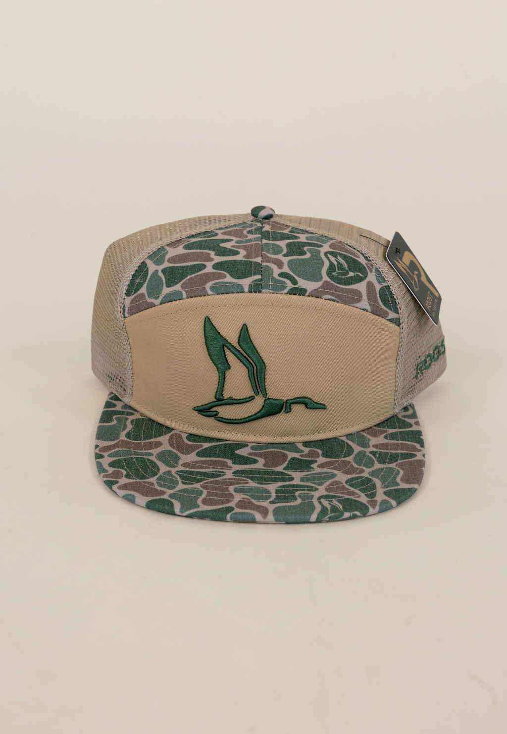 Close-up of tan and green camo waterfowl trucker cap featuring embroidered duck logo, camouflage bill and crown, and mesh back