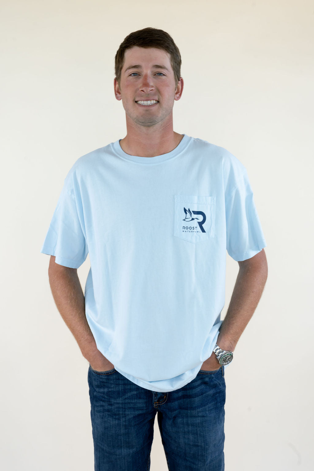 Front view of light blue Roost Waterfowl Supply Co. men’s T-shirt featuring crew neckline, relaxed fit, short sleeves, and small Roost chest logo