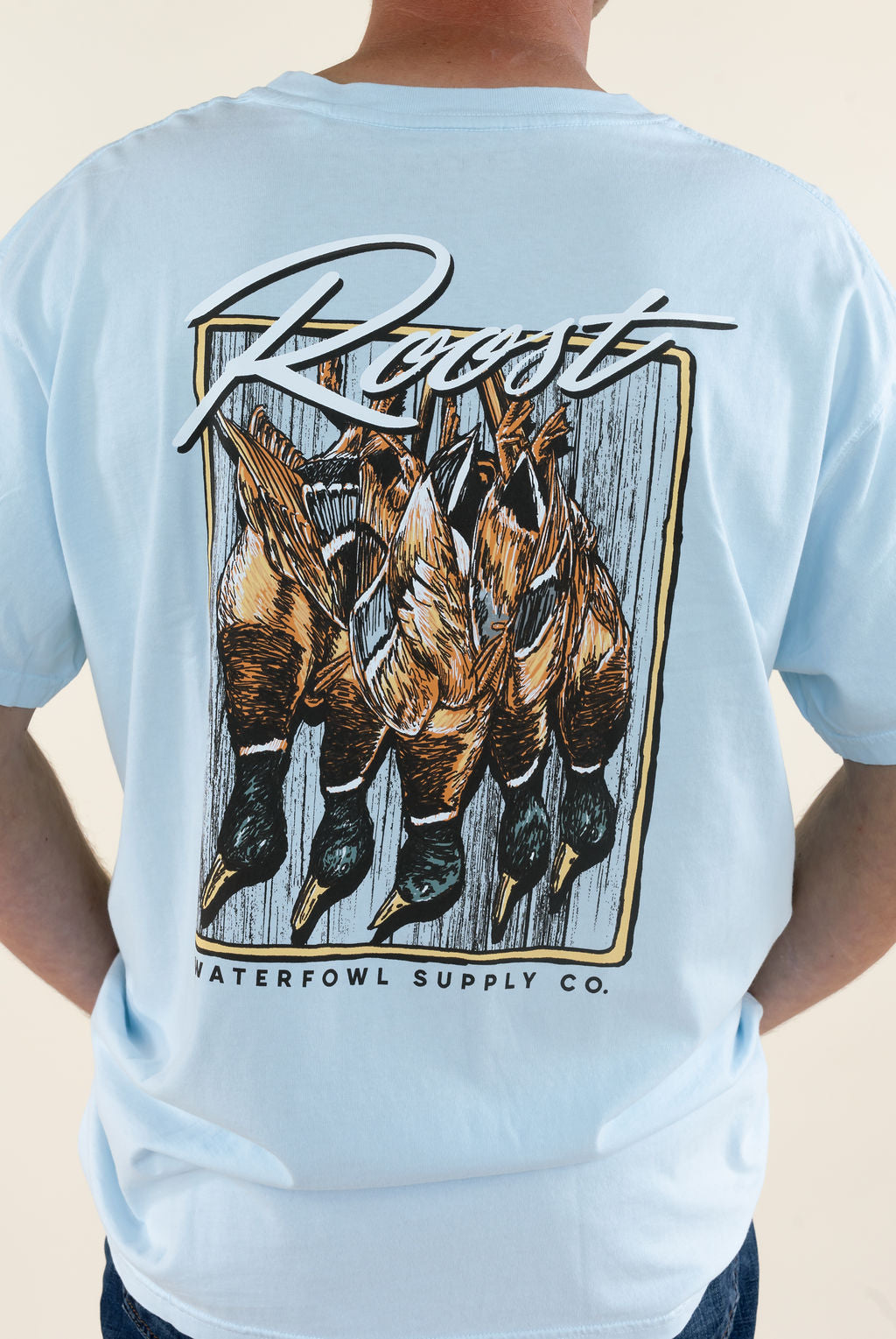 Close-up back view of light blue Roost Waterfowl Supply Co. graphic T-shirt highlighting the large hanging waterfowl hunting graphic and Roost logo lettering