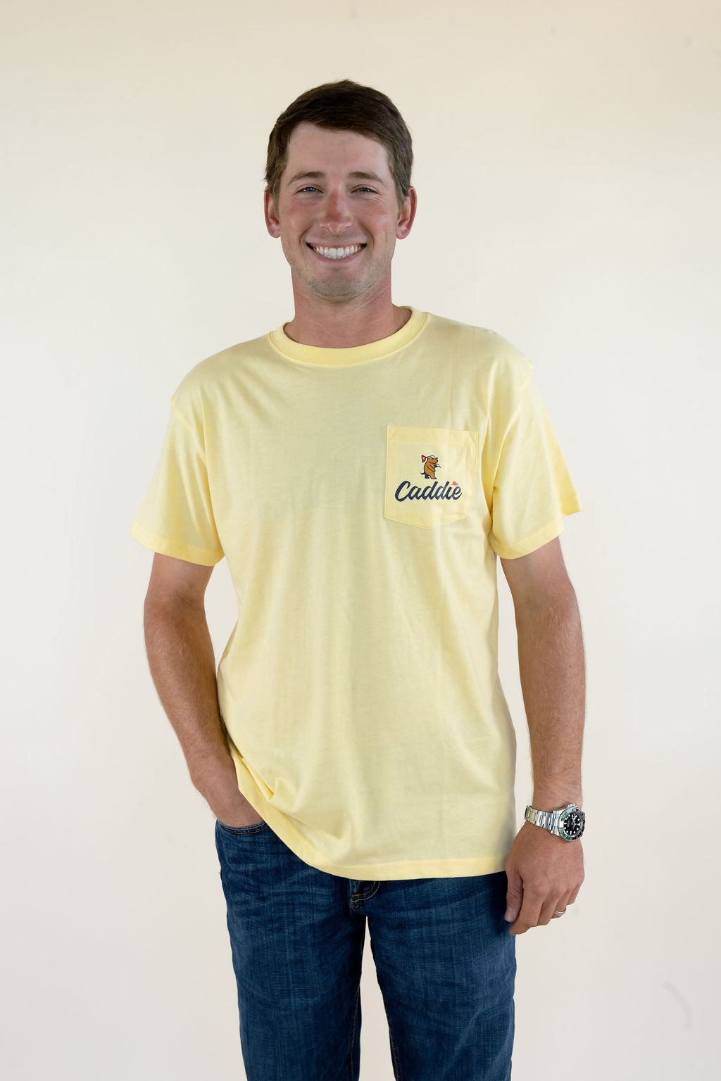 Front view of pale yellow Caddie men’s graphic T-shirt featuring crew neckline, short sleeves, relaxed fit, and small golf-inspired chest graphic