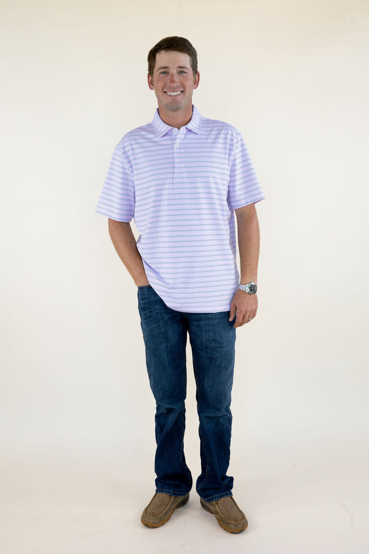 Male model wearing a purple striped short sleeve performance polo shirt with blue jeans, full-body front view.