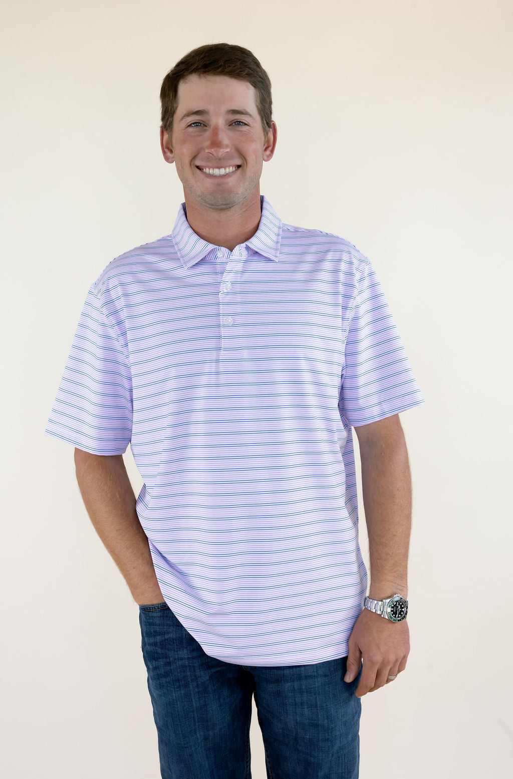Male model wearing a purple striped short sleeve performance polo shirt with a collared neckline, front view.