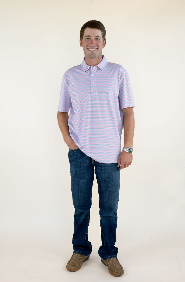 Male model wearing a cream striped short sleeve performance polo shirt with blue jeans, full-body front view.