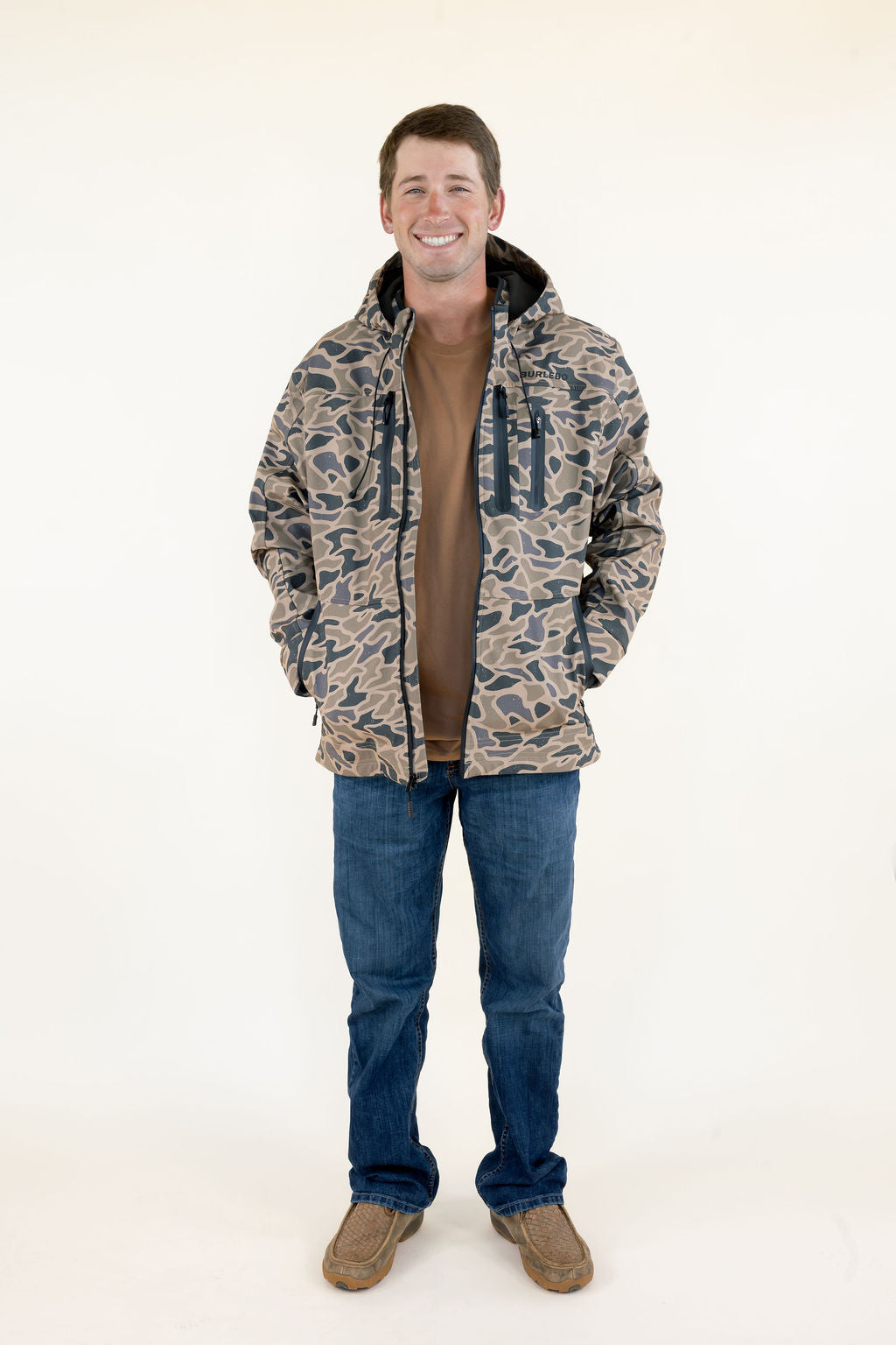 Male model wearing the Burlebo Challenger Jacket in Gauge Camo with blue jeans, full-body front view.