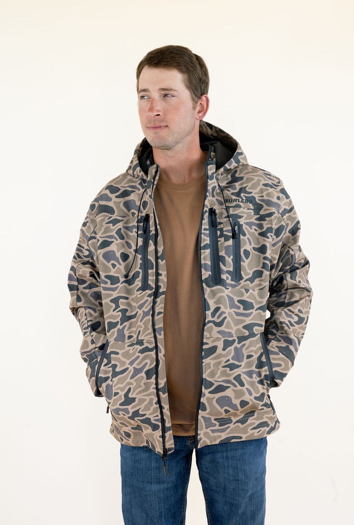 Front view of male model wearing the Burlebo Challenger Gauge Camo waterproof hunting jacket open over a brown shirt.
