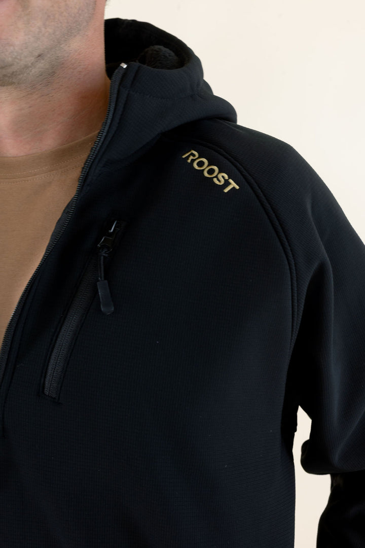 Close-up of the black Roost Defender Pullover showing the quarter-zip neckline, hood and Roost logo detail.