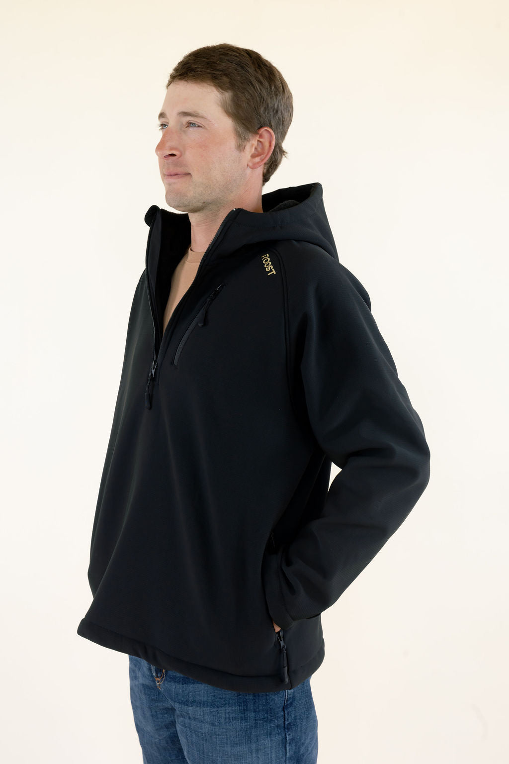 Side view of male model wearing the black Roost Defender soft shell pullover showing the relaxed fit and hood.