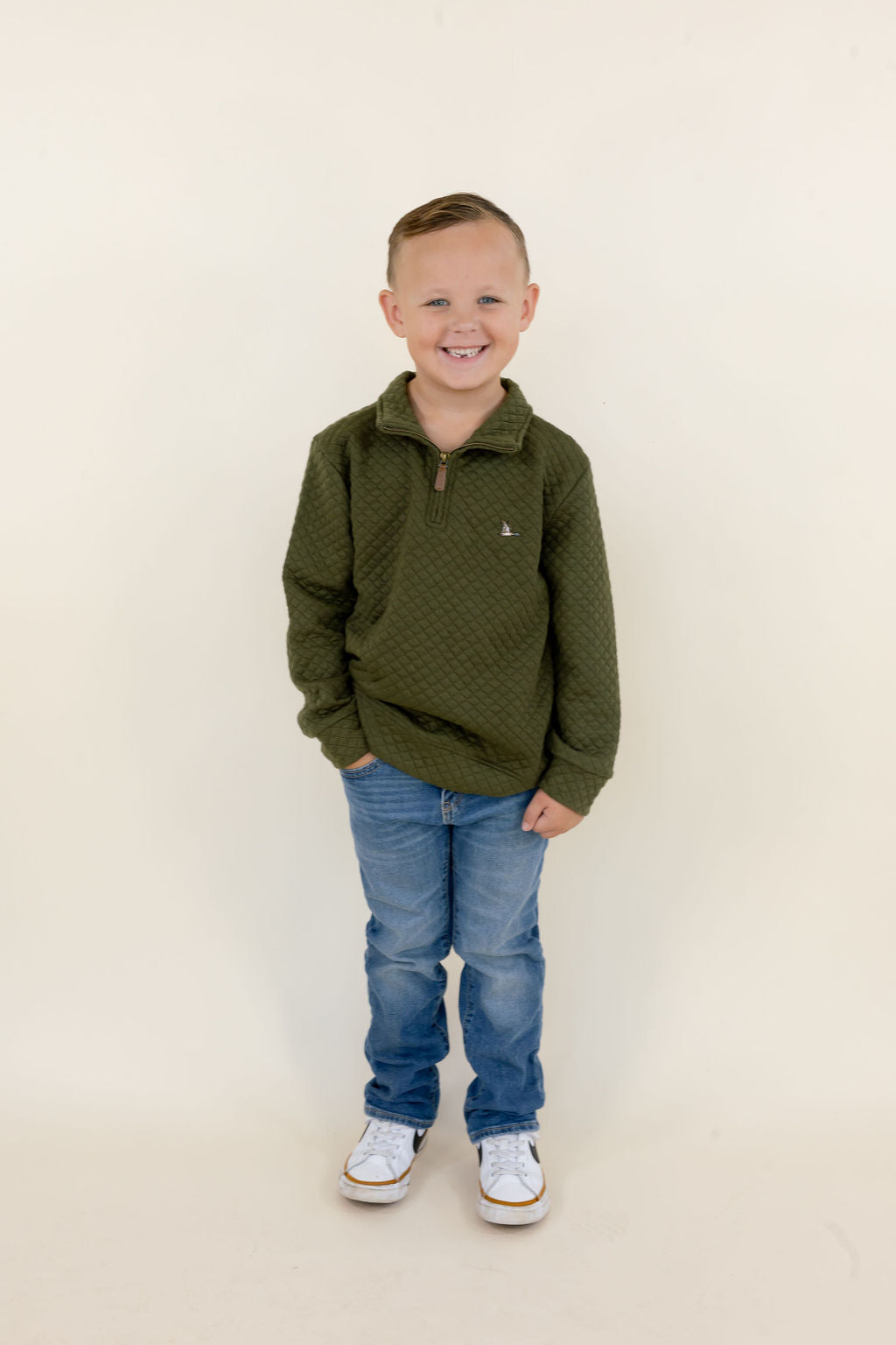 Youth model wearing the green Roost Drake quarter zip pullover with blue jeans, full-body front view.