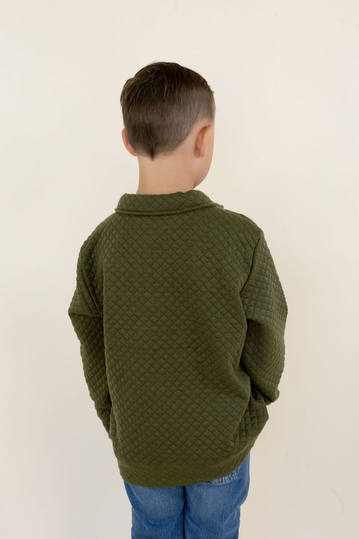 Back view of youth model wearing the green Roost Drake pullover showing the solid green design and elastic hem.
