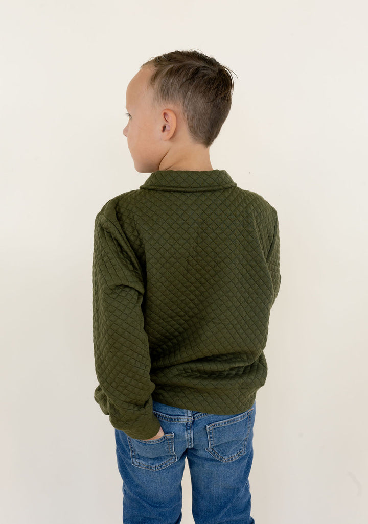 Three-quarter back view of youth model wearing the green Roost Drake quarter zip pullover with blue jeans.