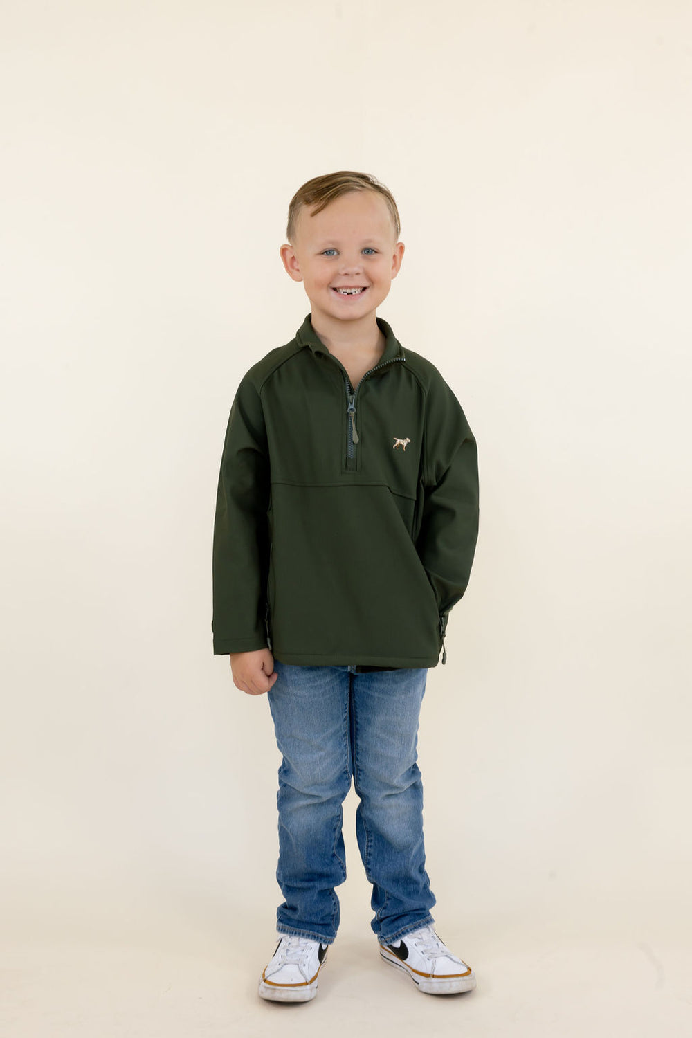 Youth model wearing the green Dogwood soft shell quarter zip pullover with blue jeans and sneakers, full-body front view.