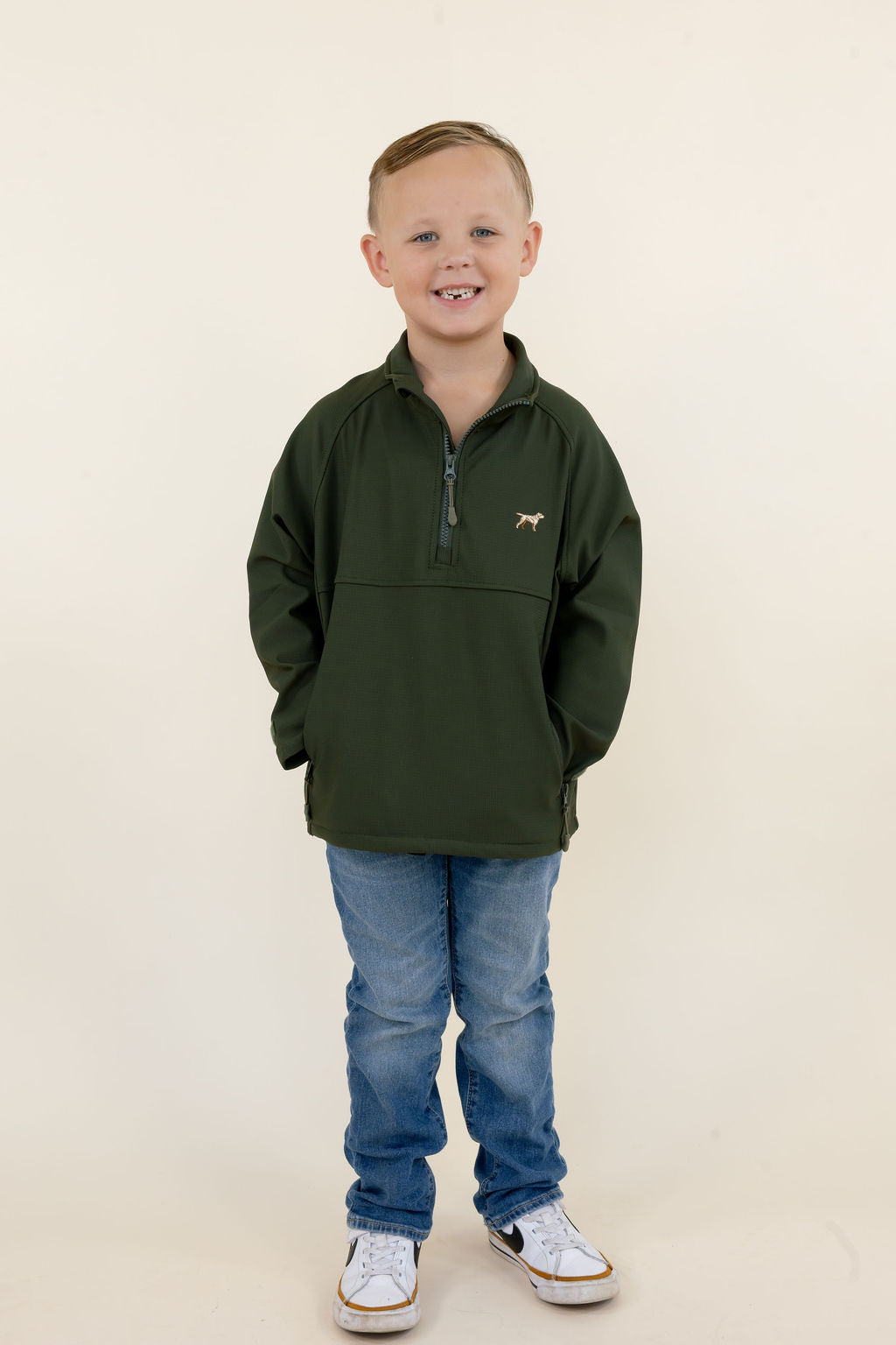 Youth model wearing the green Dogwood quarter zip pullover with blue jeans, full-length studio view.