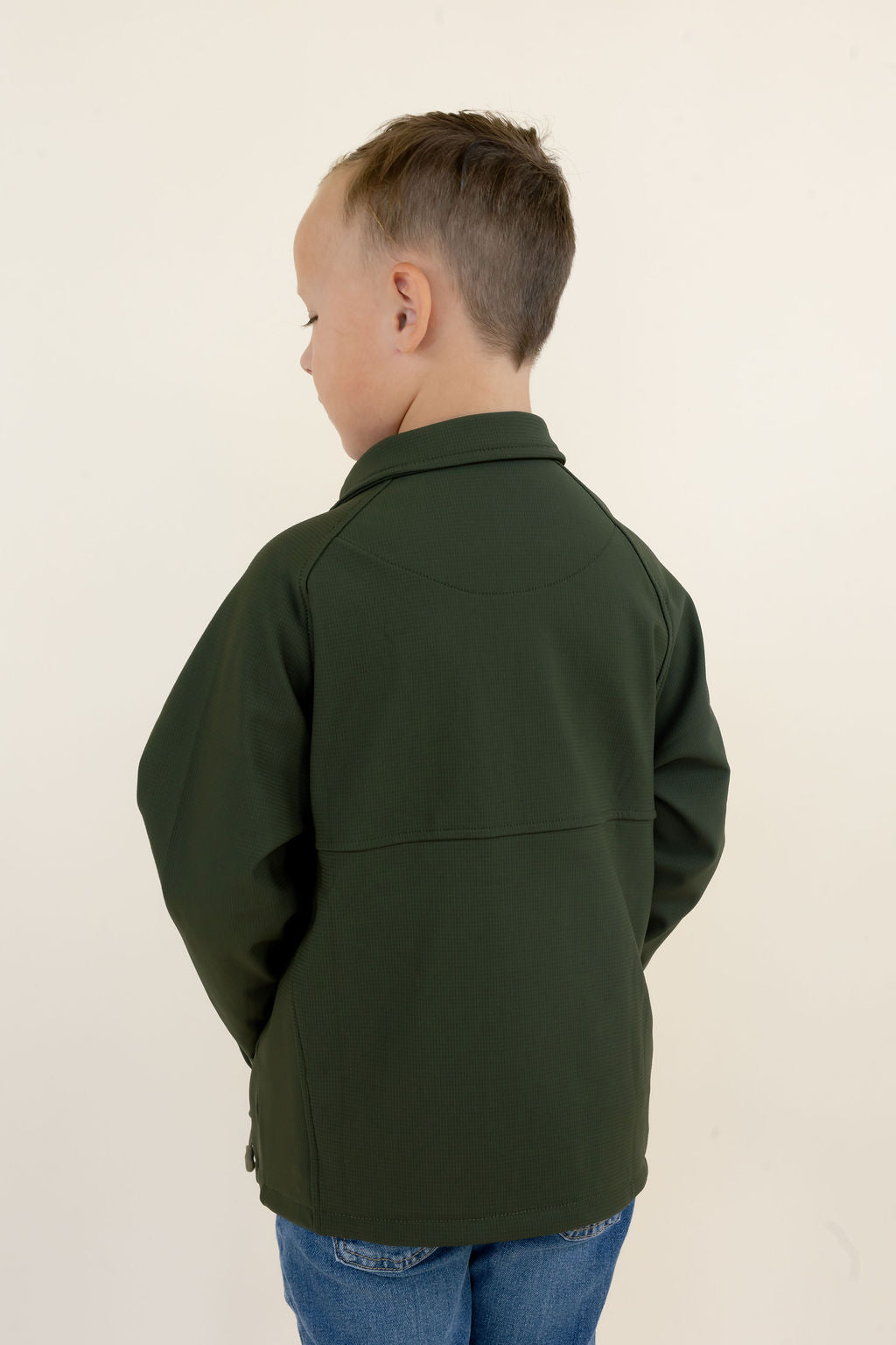 Back view of youth model wearing the green Dogwood Pullover showing the solid green soft-shell design and fit.
