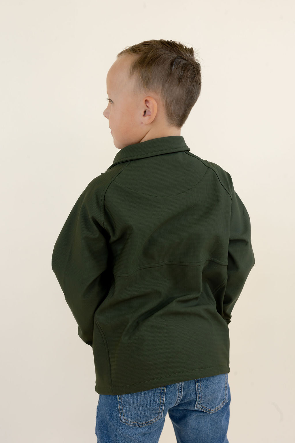 Three-quarter back view of youth model wearing the green Dogwood quarter zip pullover showing the rear silhouette and elastic hem.