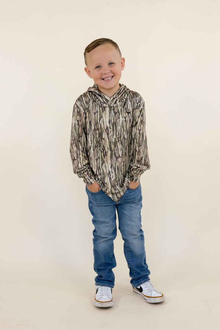 Full-length front view of boys camouflage performance hoodie featuring an attached hood and long sleeves, styled with blue denim jeans and sneakers.