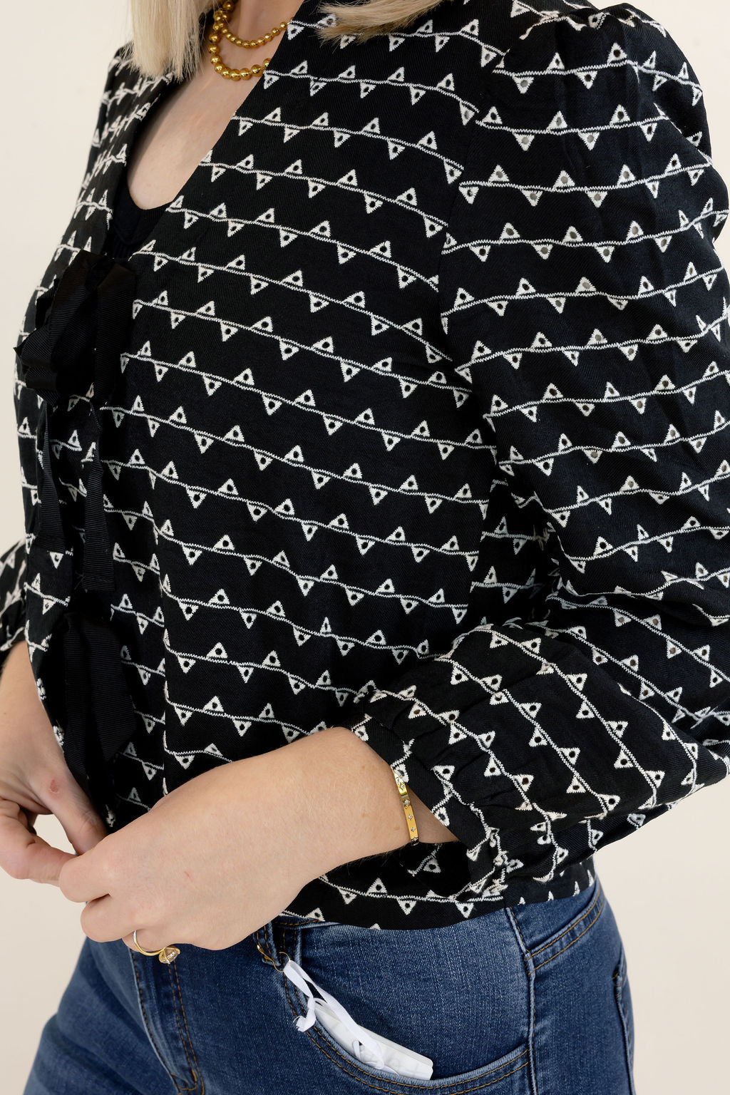 Close-up of black and white textured sweater jacket showing the puff sleeve design, gathered cuff, and contrasting black bow details