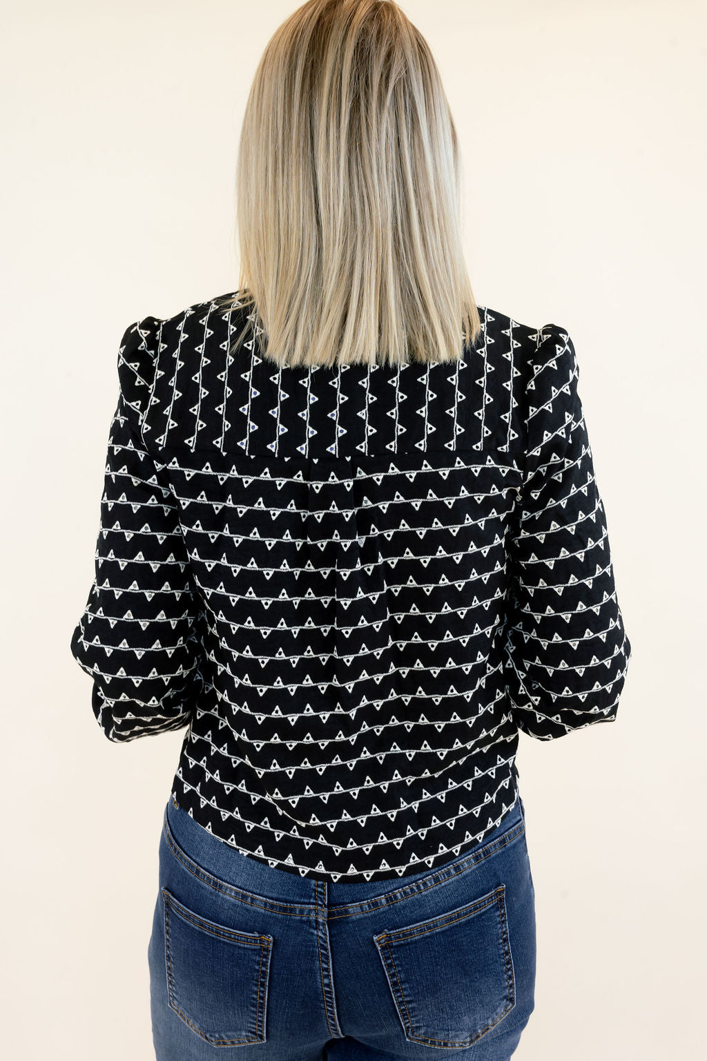 Close-up back view of black and white textured sweater jacket highlighting the allover geometric pattern, structured shoulders, long sleeves, and cropped hem