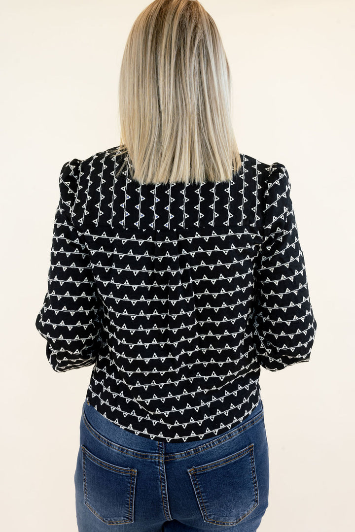 Close-up back view of black and white textured sweater jacket highlighting the allover geometric pattern, structured shoulders, long sleeves, and cropped hem