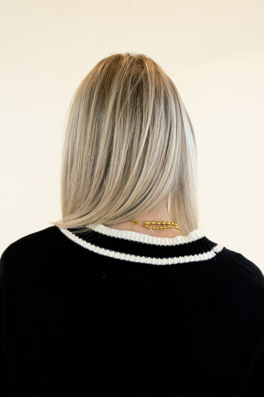 Close-up back view of black cardigan highlighting the white contrast trim around the neckline, smooth knit texture, and relaxed shoulder fit