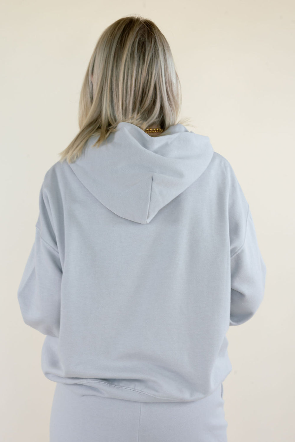 Back close-up of First Quarter Hoodie in Silverlake showing oversized fit, attached hood, dropped shoulders, and ribbed hem in light blue-gray fleece.