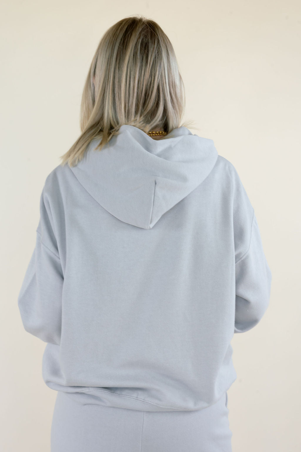 Back close-up of First Quarter Hoodie in Silverlake showing oversized fit, attached hood, dropped shoulders, and ribbed hem in light blue-gray fleece.