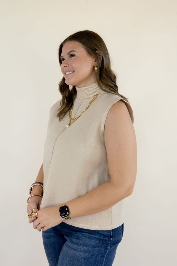 Three-quarter view of cream sleeveless mock neck sweater top highlighting the high neckline, sleeveless design, and relaxed everyday fit