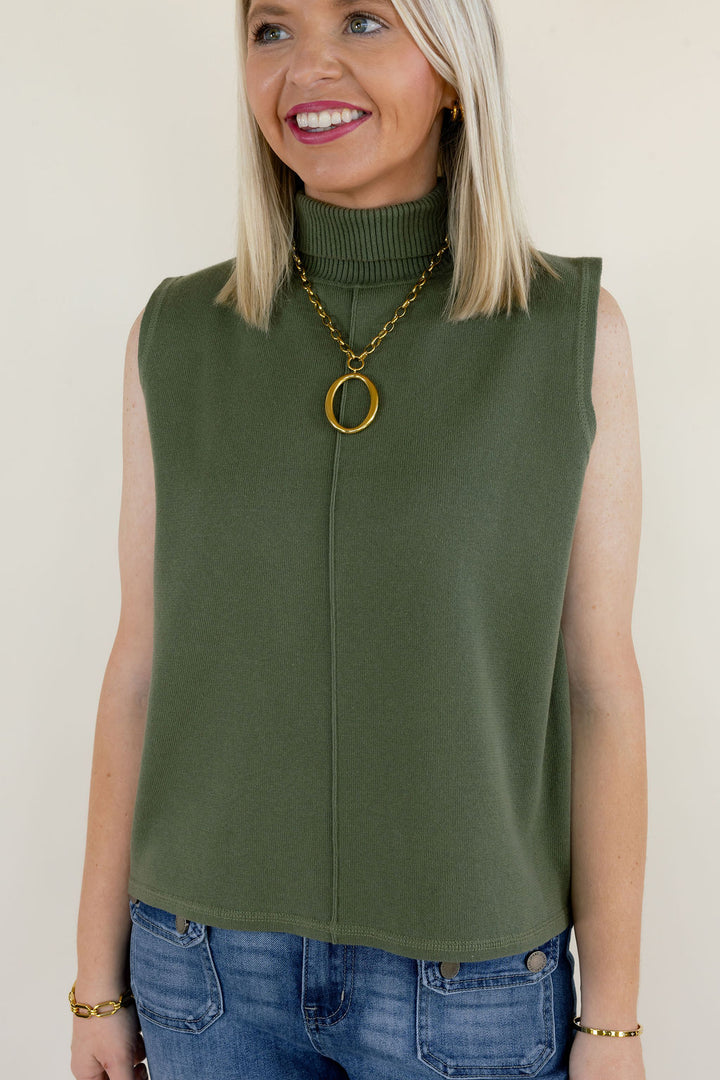 Close-up of olive green sleeveless mock neck sweater top featuring a high neckline, subtle front seam detail, and relaxed fit