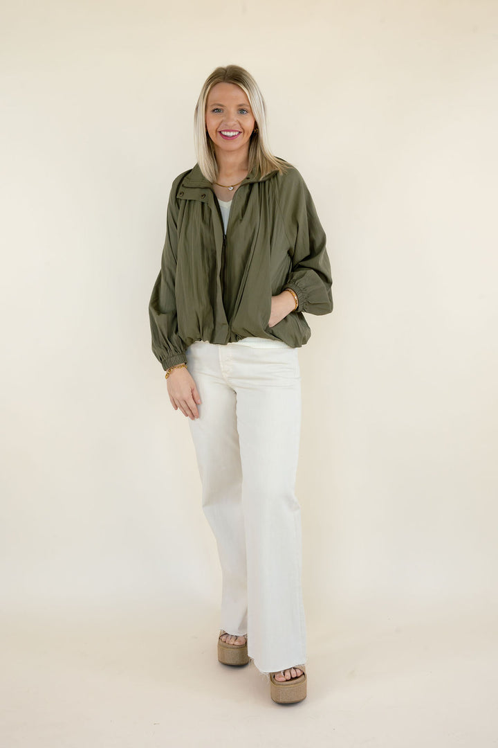 Woman modeling olive green collared balloon sleeve blouse with gathered neckline, relaxed fit, and white wide leg pants
