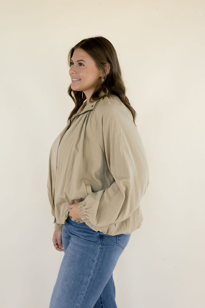 Side profile of beige collared blouse featuring oversized balloon sleeves, gathered fabric, and relaxed silhouette