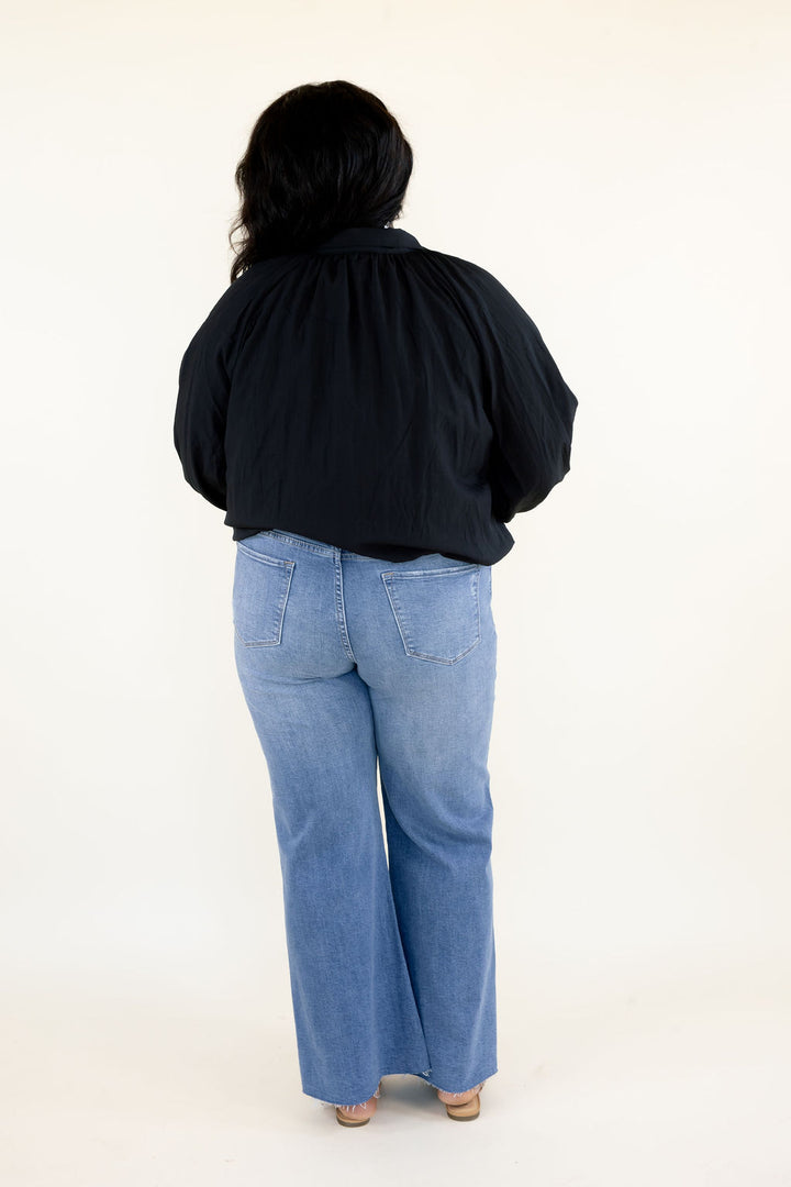 Back view of black balloon sleeve blouse showing gathered fabric across the shoulders, relaxed silhouette, and long sleeves