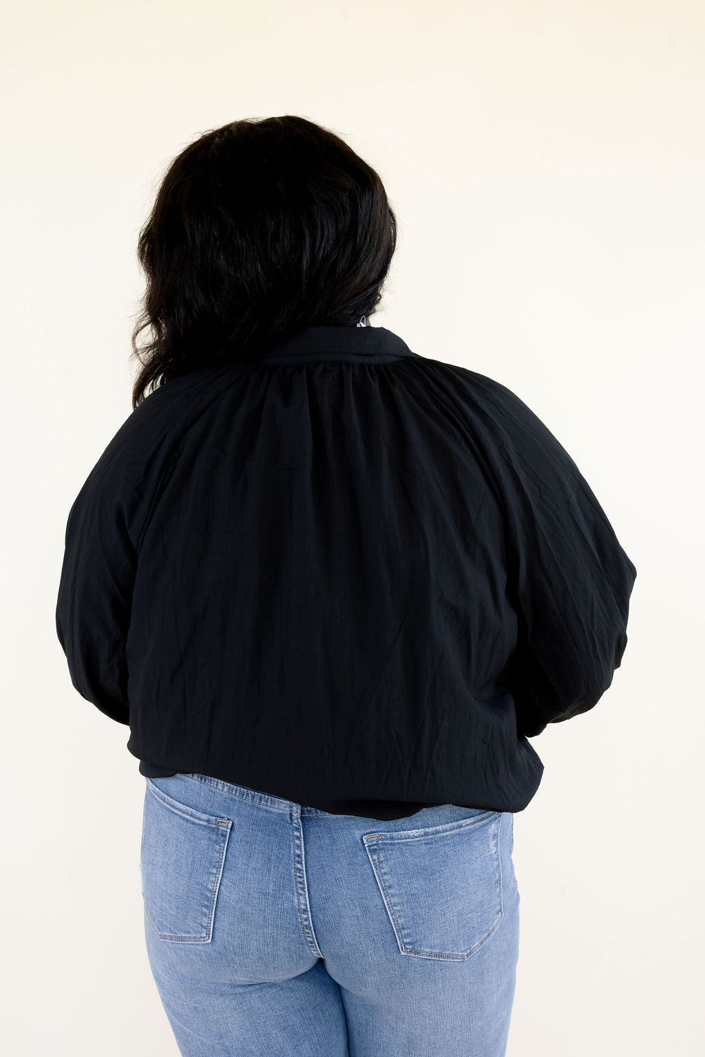 Close-up back view of black collared blouse highlighting the gathered back neckline, long balloon sleeves, and relaxed silhouette