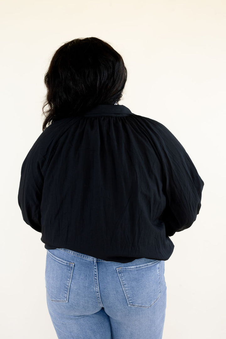 Close-up back view of black collared blouse highlighting the gathered back neckline, long balloon sleeves, and relaxed silhouette