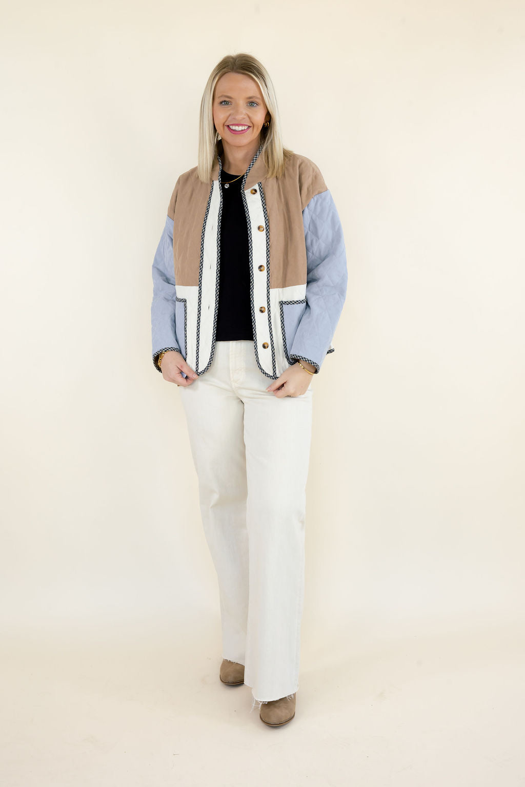 Woman modeling camel brown, light blue, and ivory colorblock quilted jacket with button front, contrasting trim, and patch pockets styled with white wide leg pants