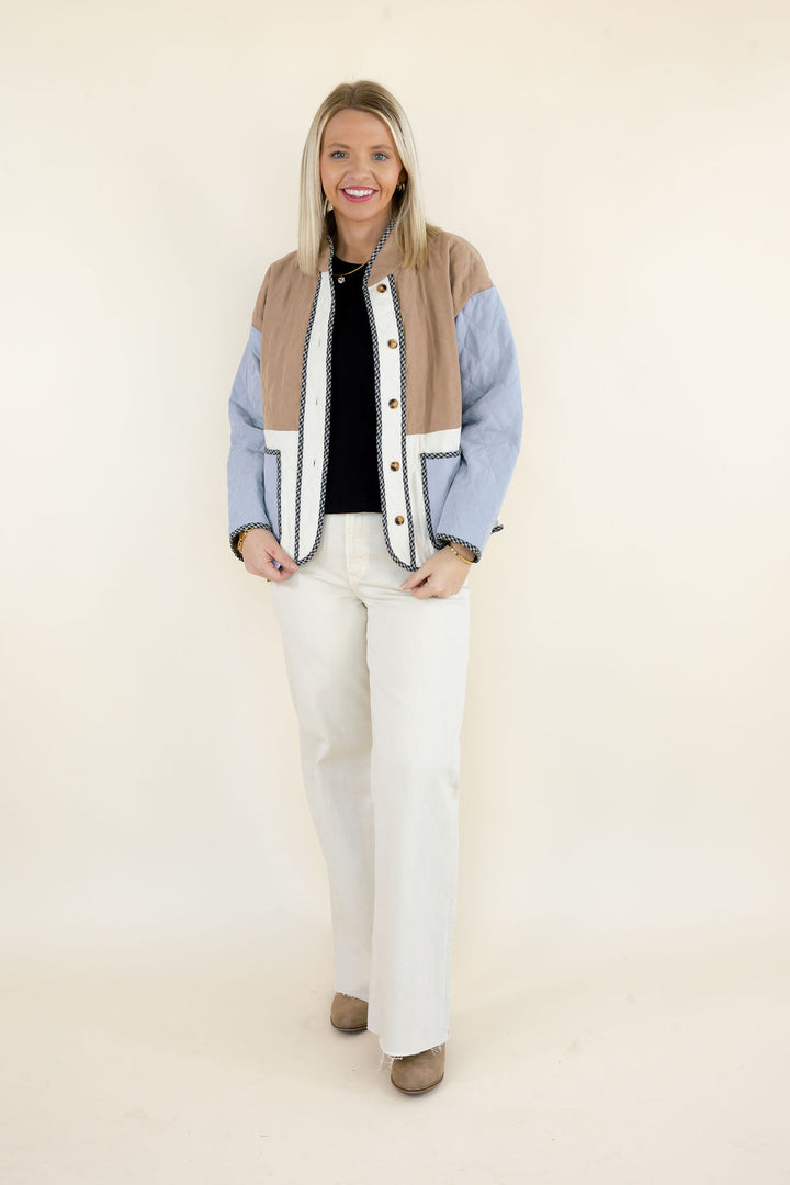 Woman modeling camel brown, light blue, and ivory colorblock quilted jacket with button front, contrasting trim, and patch pockets styled with white wide leg pants