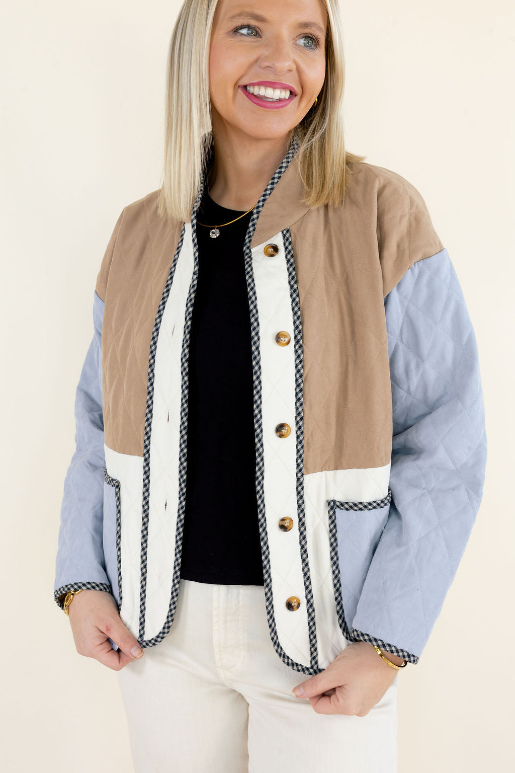Close-up of colorblock quilted jacket highlighting the camel brown quilted upper panel, ivory button placket, light blue sleeves, and decorative contrast trim