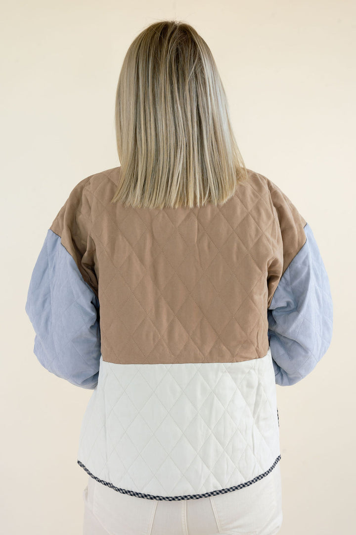 Close-up back view of colorblock quilted jacket highlighting the camel brown diamond quilted upper panel, ivory lower section, and light blue sleeves