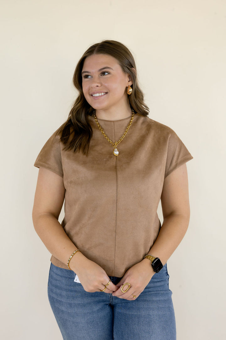 Close-up of brown faux suede short sleeve top showing the round neckline, center-front seam, soft textured fabric, and relaxed silhouette.