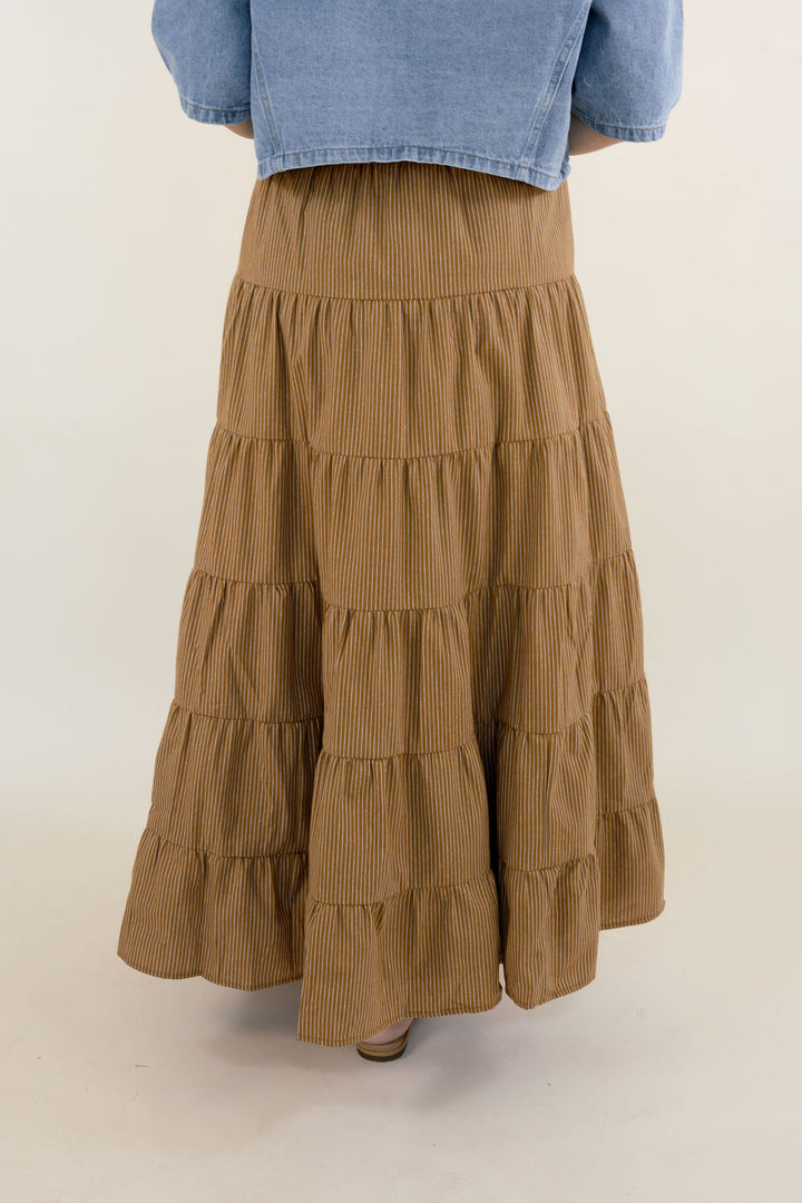 Back view of camel brown tiered maxi skirt for women featuring a comfortable elastic waistband, gathered tiers, and flowing maxi length.