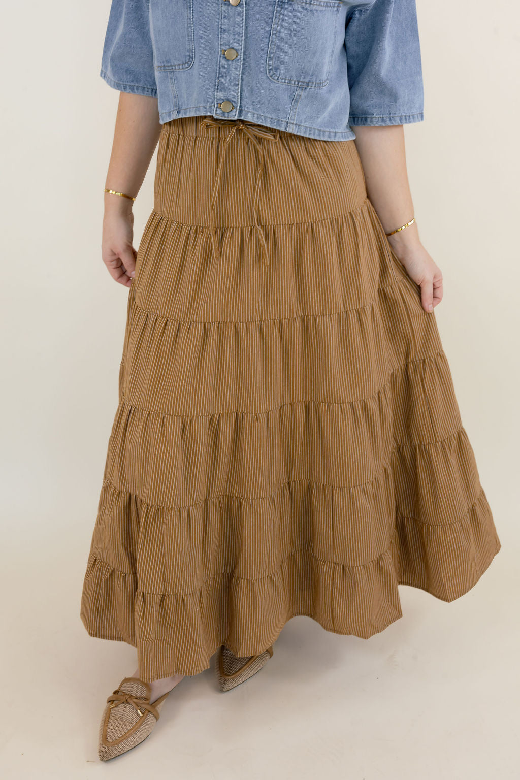 Camel brown boho maxi skirt featuring a stretchy elastic waistband, tiered ruffle detailing, and flowy lightweight silhouette styled with a denim top.