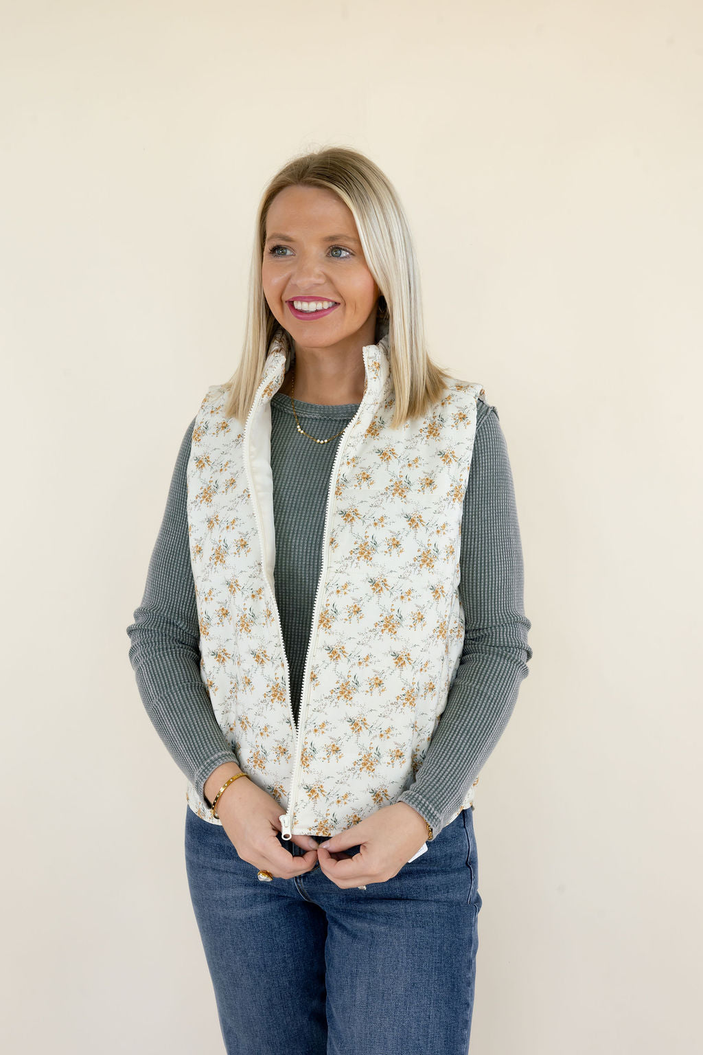Three-quarter view of woman modeling ivory quilted floral vest featuring a high neckline, zip front, and relaxed sleeveless silhouette
