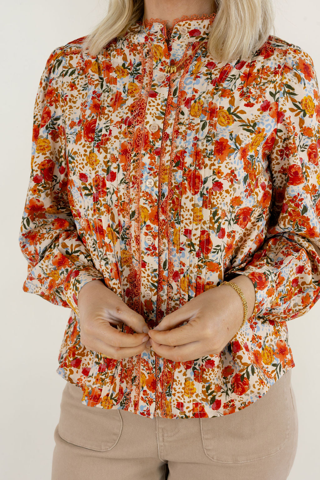 Close-up of cream multi floral blouse showing colorful floral pattern, delicate neckline details, gathered fabric, and long sleeves.