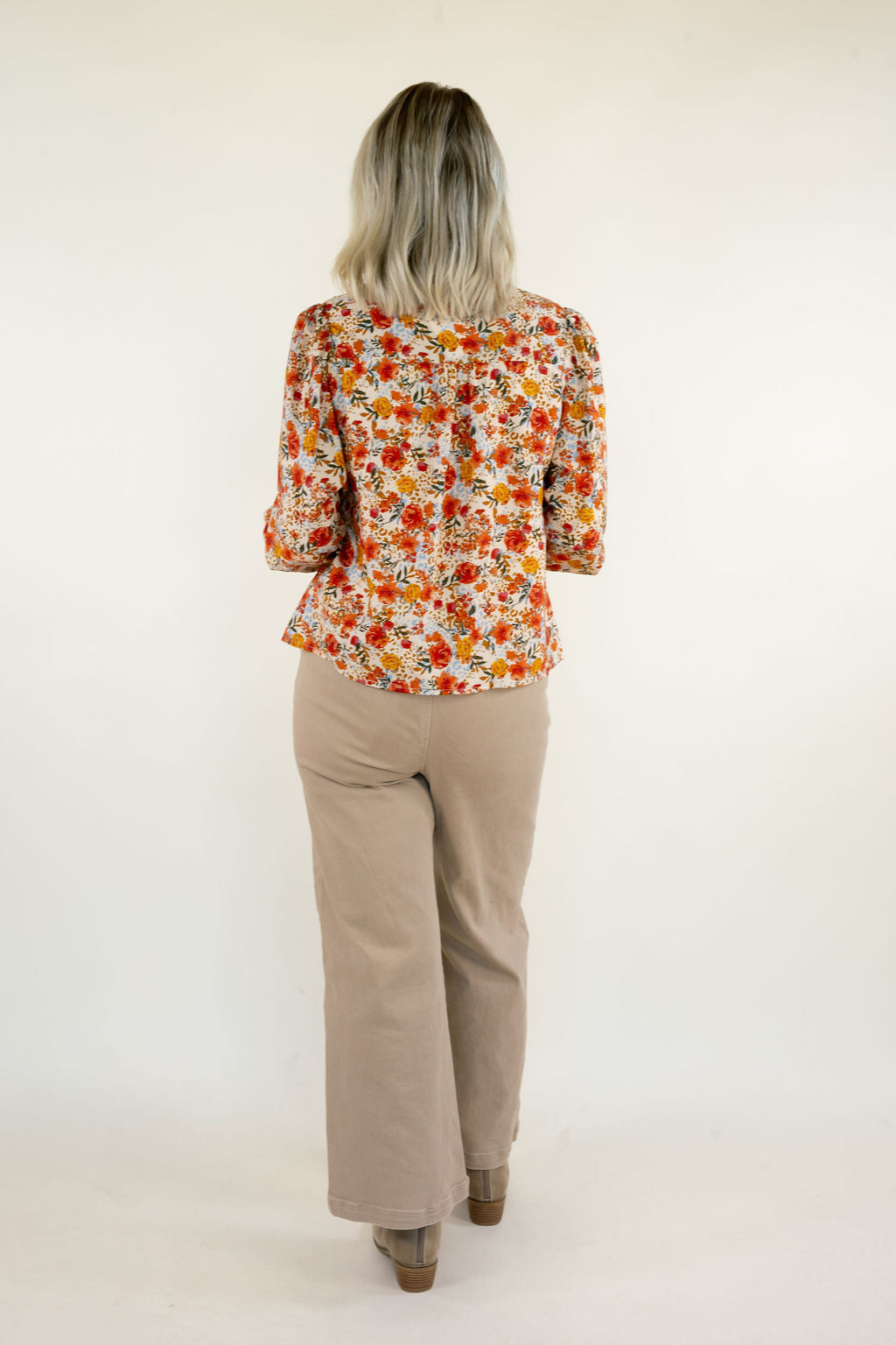 Back view of cream multi floral print blouse showing the colorful orange and yellow floral pattern, long sleeves, and relaxed silhouette.