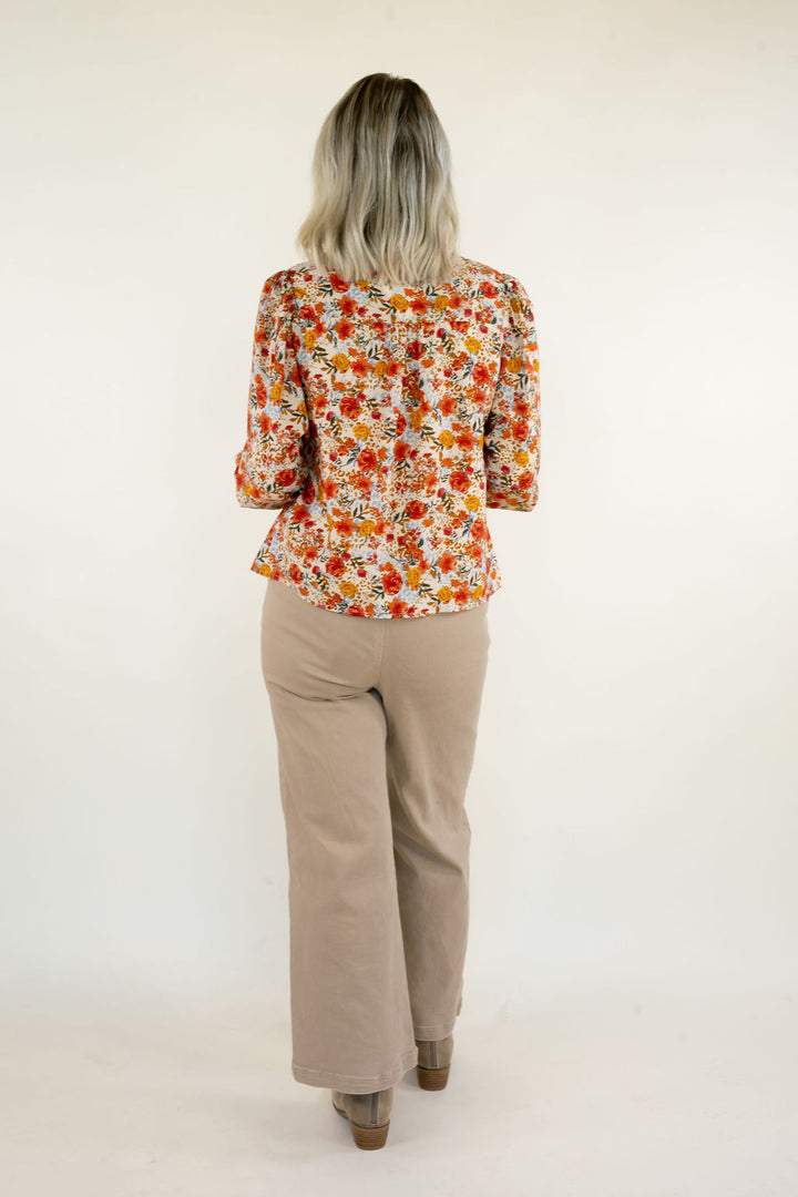 Back view of cream multi floral print blouse showing the colorful orange and yellow floral pattern, long sleeves, and relaxed silhouette.