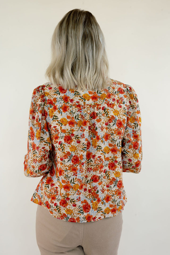 Back view of cream multi floral print blouse showing the colorful orange and yellow floral pattern, long sleeves, and relaxed silhouette.