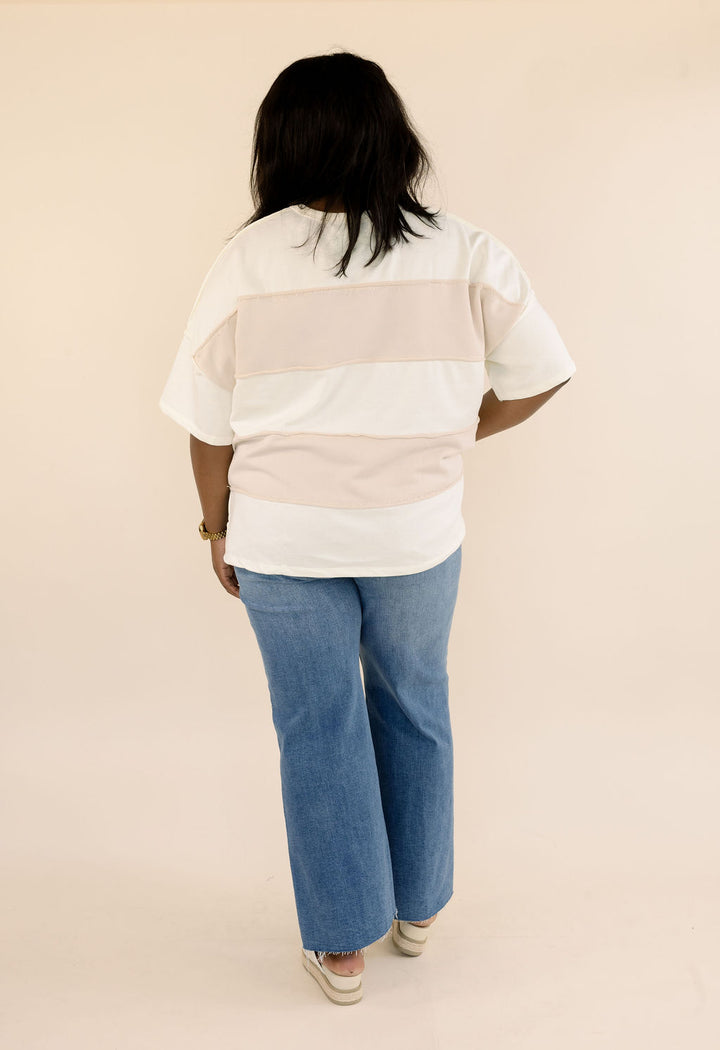 Full back view of plus size taupe and cream color block top showing short sleeves, relaxed fit, and horizontal color blocking.
