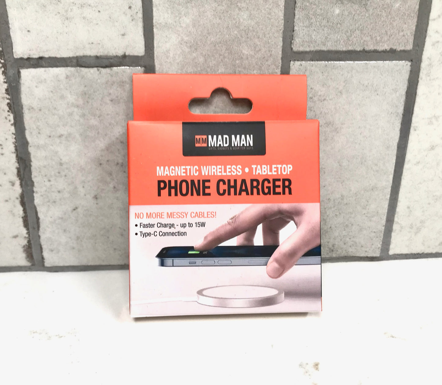 Packaging of a magnetic wireless tablet phone charger with 'Mad Man' branding on a tiled floor background.