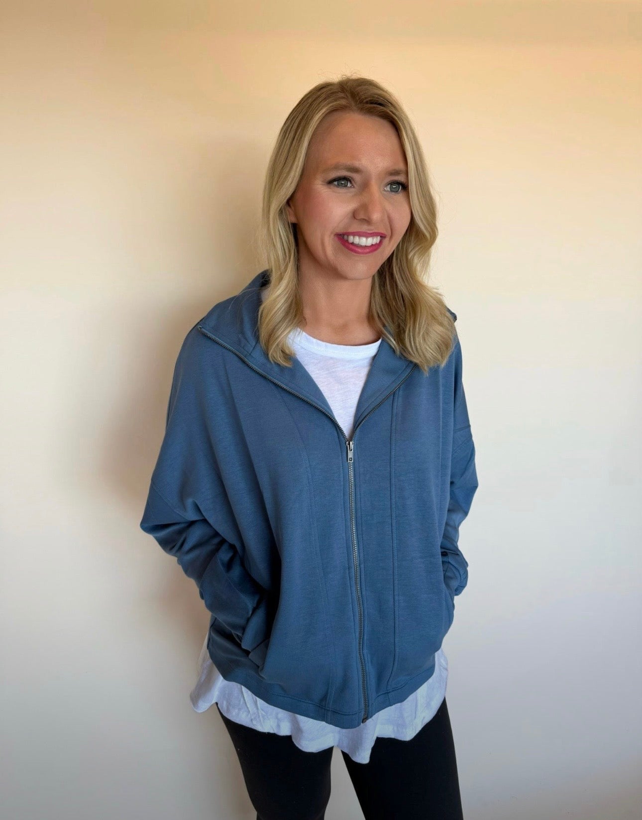 Woman wearing a blue zip-up hoodie against a plain background