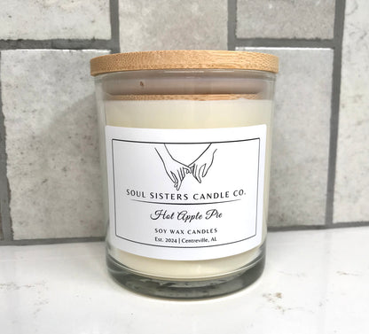 Scented candle with a wooden lid and 'Soul Sisters Candle Co' label on a gray tiled background.